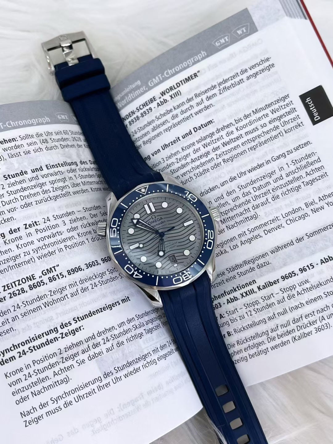 Omega Blue watch with a detailed face on an open book