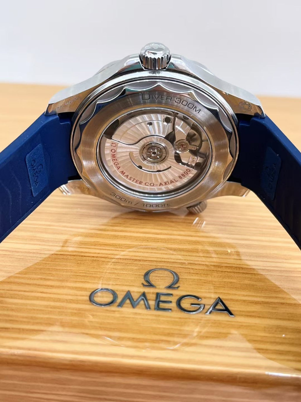Omega watch with visible movement on a wooden display stand