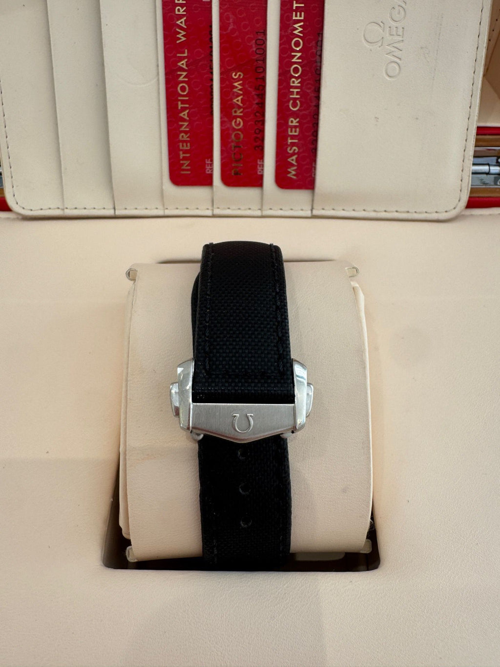 Black watch strap on a white surface with Omega branding visible