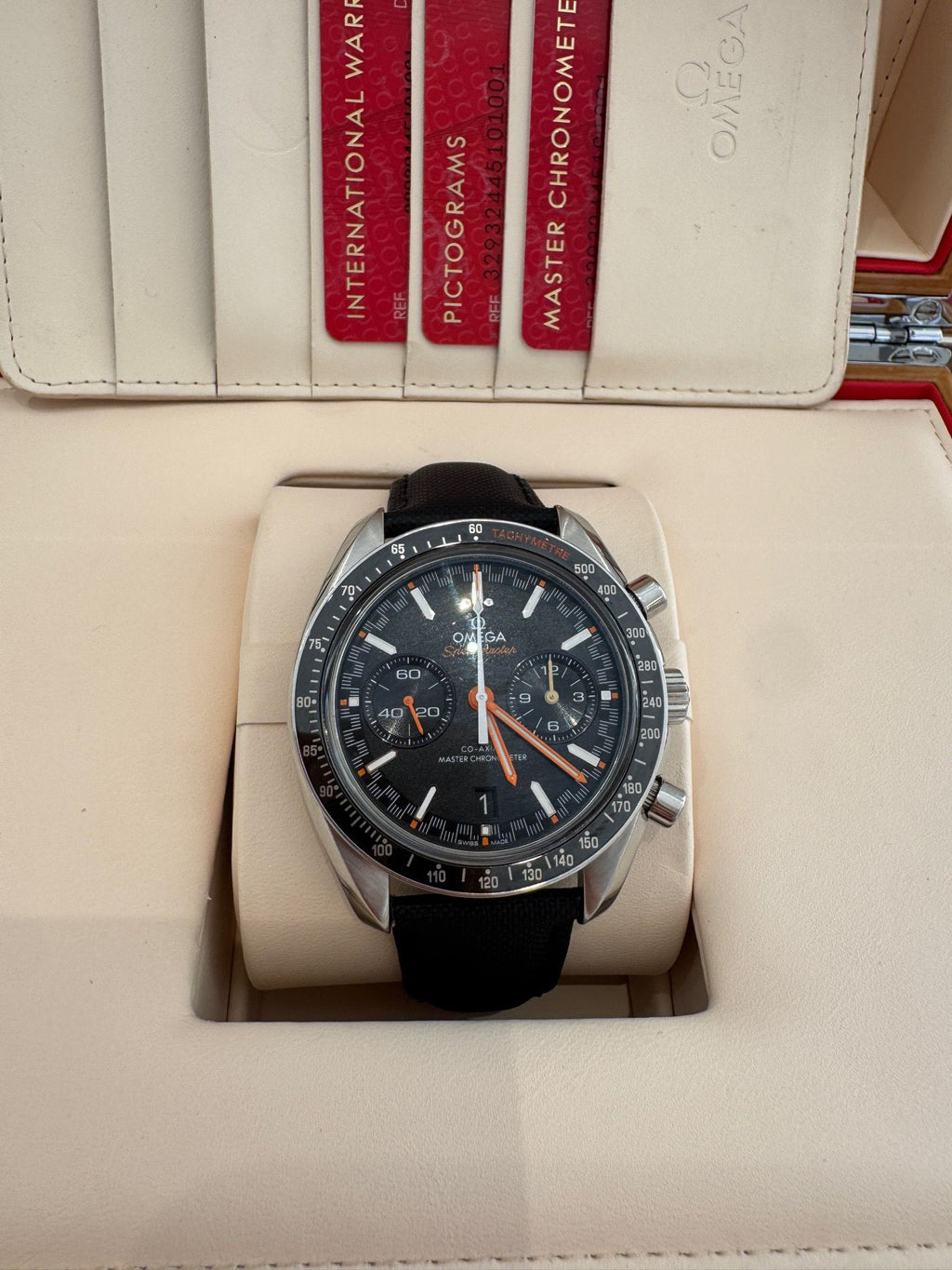 Omega watch with black strap on a display stand, branded packaging in the background