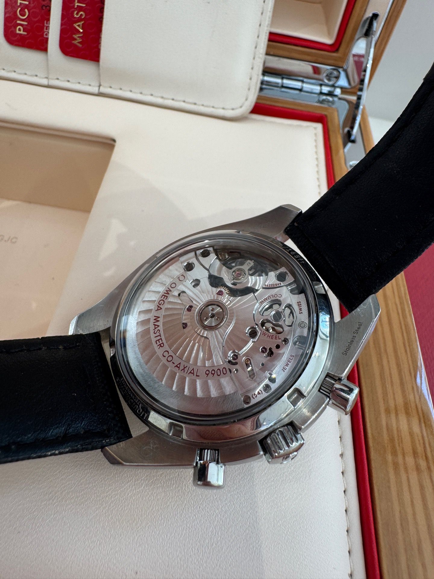 Watch with black strap and visible mechanism on a white surface